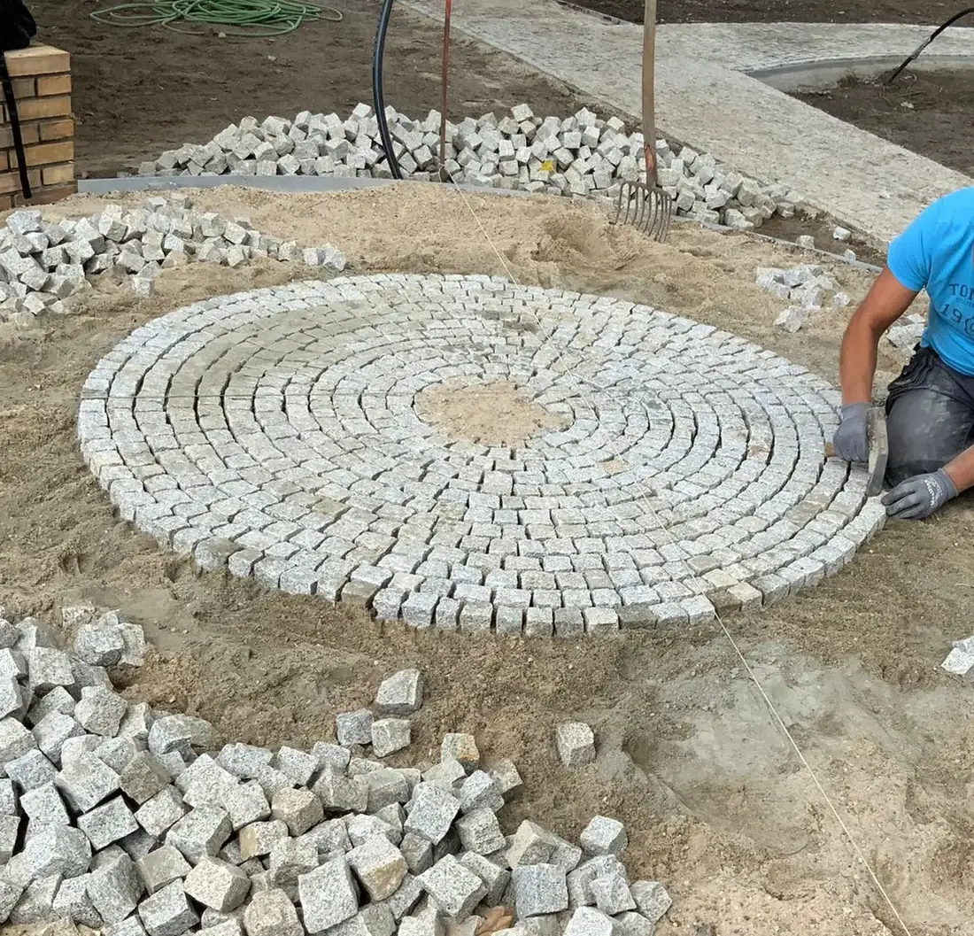 Kreisförmig verlegtes Granit-Kleinpflaster im Sandbett während der Bauphase
