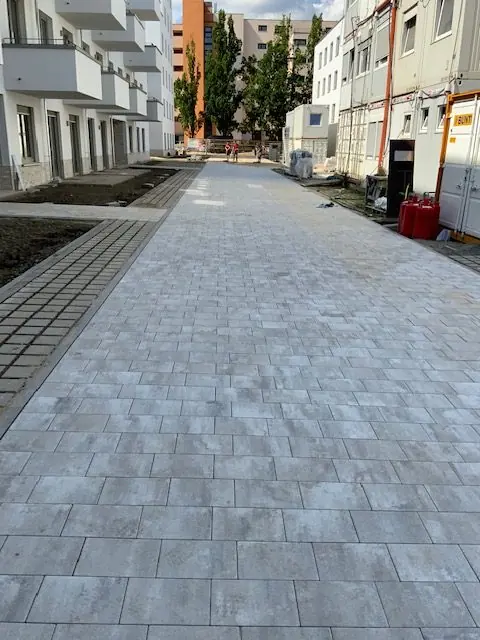 Gepflasterter Gehweg aus grauen Platten entlang neuer Wohnhäuser